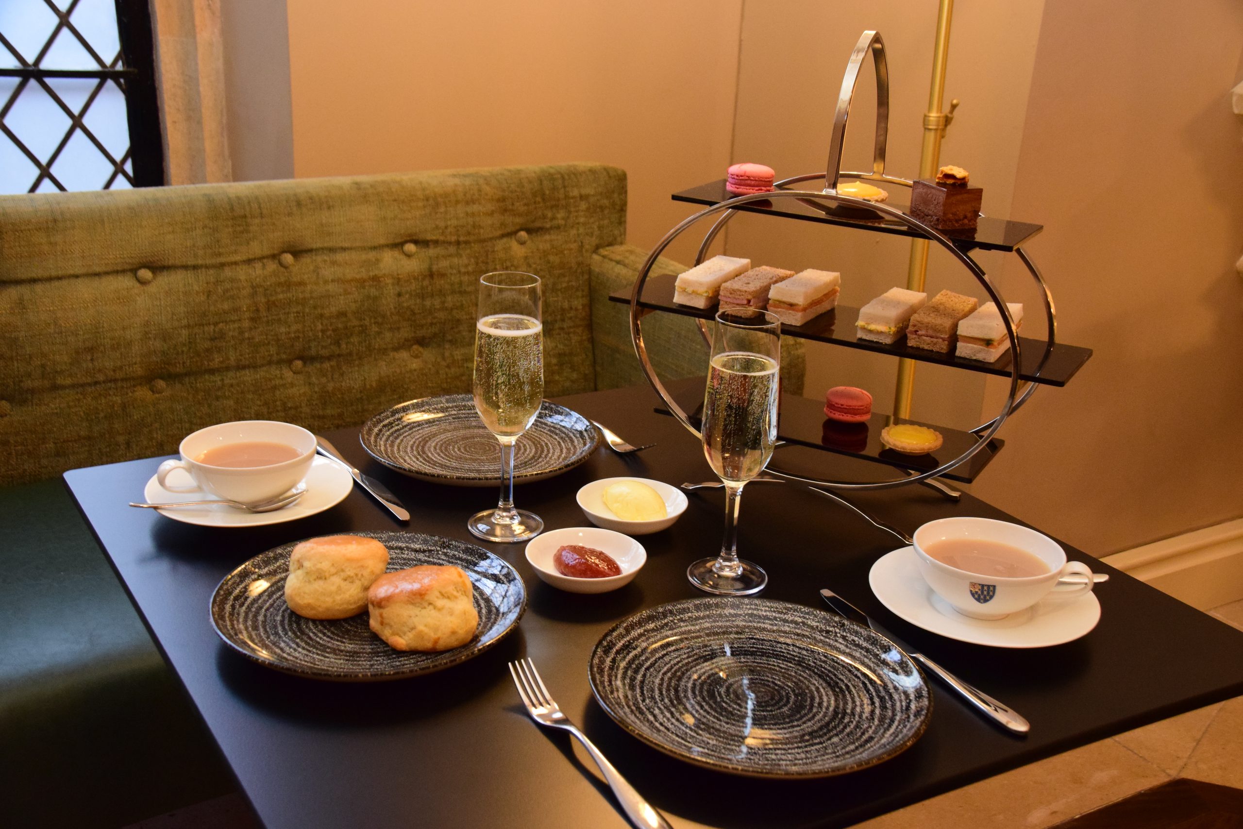 Table set up for afternoon tea with a selection of sandwiches, sweets, scones and drinks