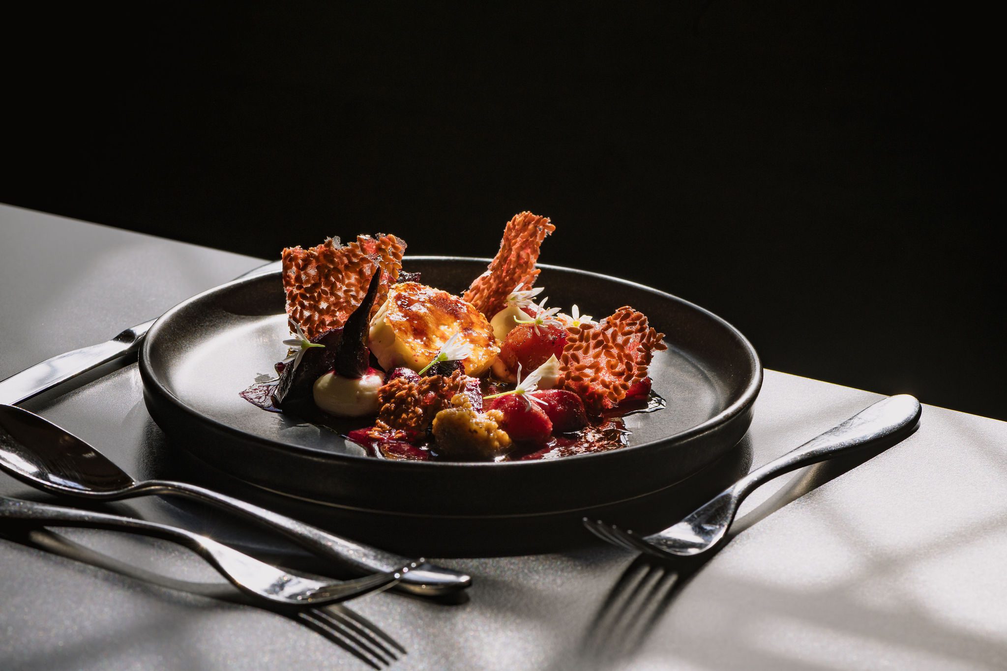 A detailed photo of Hertiage Beetroot and Ragstone Goats Cheese Salad plated on a black plate