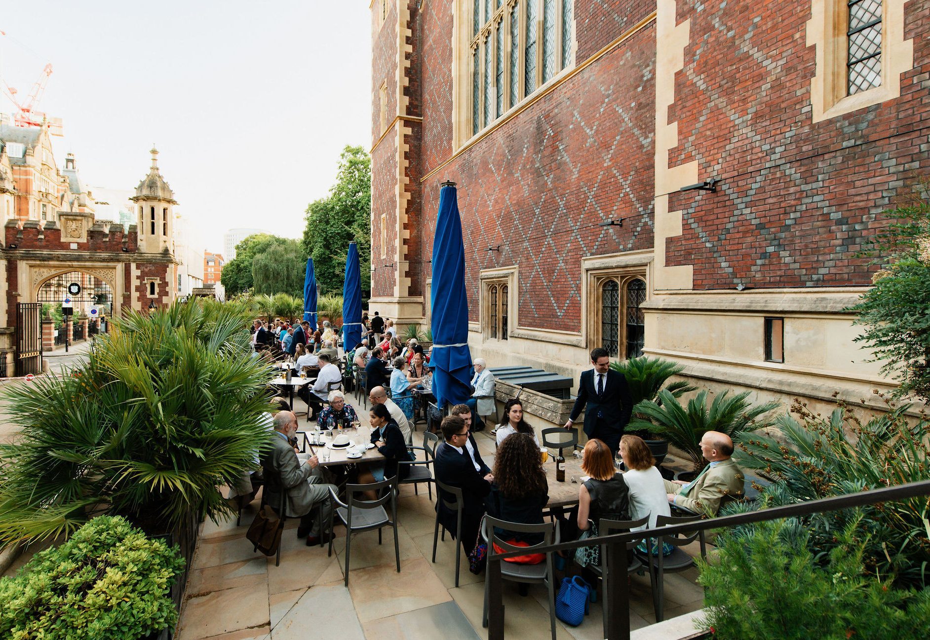 The photo shows members enjoying drinks in the sunshine on the MCR restaurant and bar terrace at lincoln's Inn