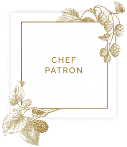 Sign saying chef patron in square with floral decorations