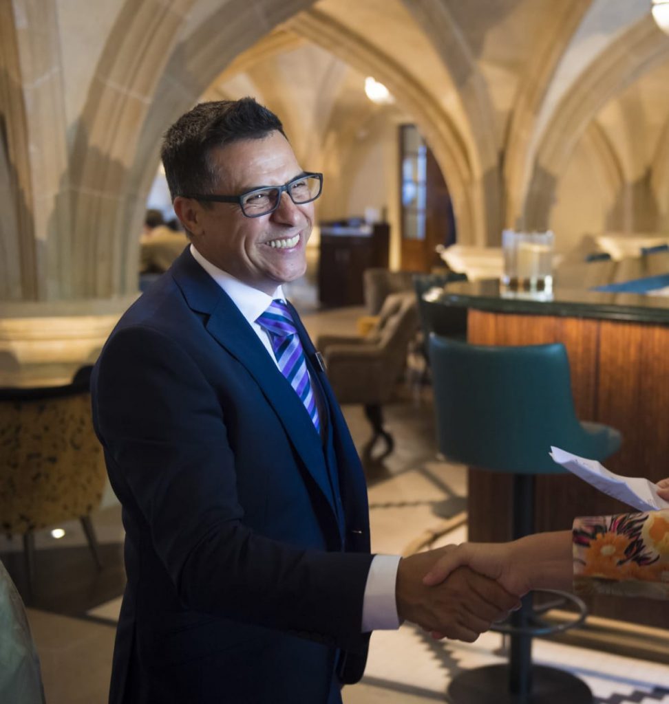 Member of staff smiling and shaking hands in restaurant and bar with domed ceilings