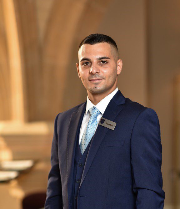 Member of staff posing for photo in historic hall