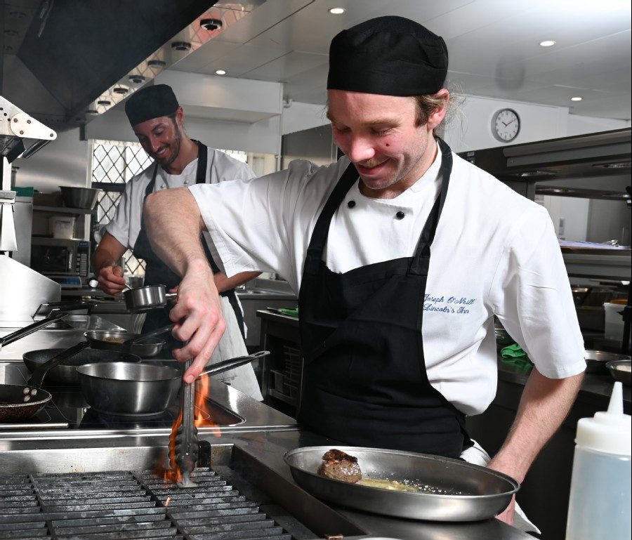 Two chefs preparing and cooking food in kitchen